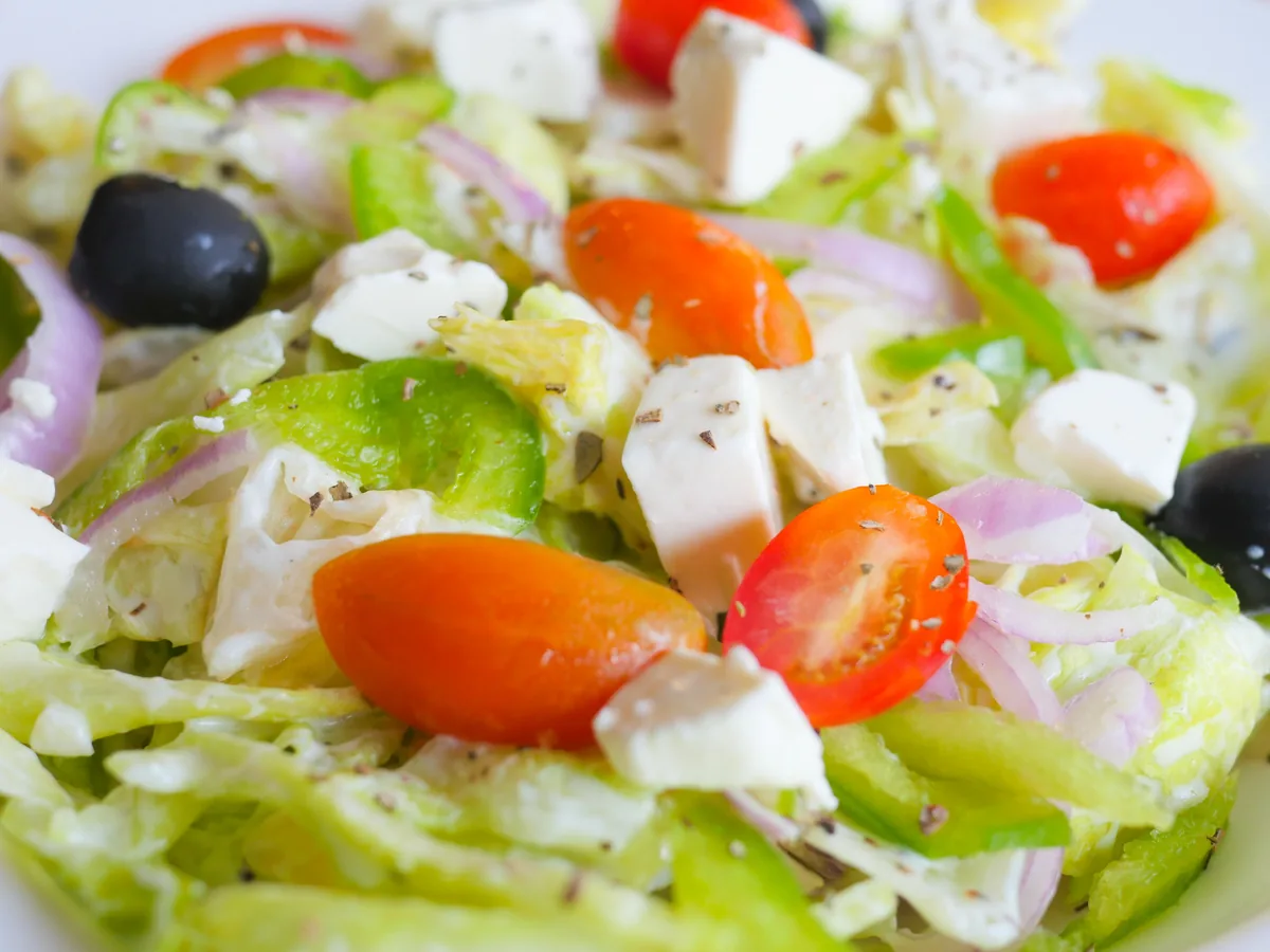 En græsk salat med cherrytomater, hvide feta-terninger, sorte oliven, rødløg og grøn peber